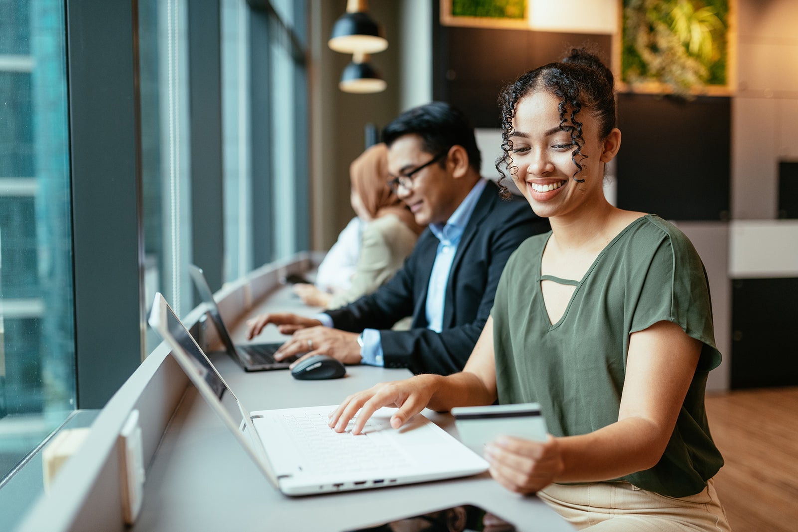 Curly African American entrepreneur working as digital nomad. Businesswoman using credit card for online payments