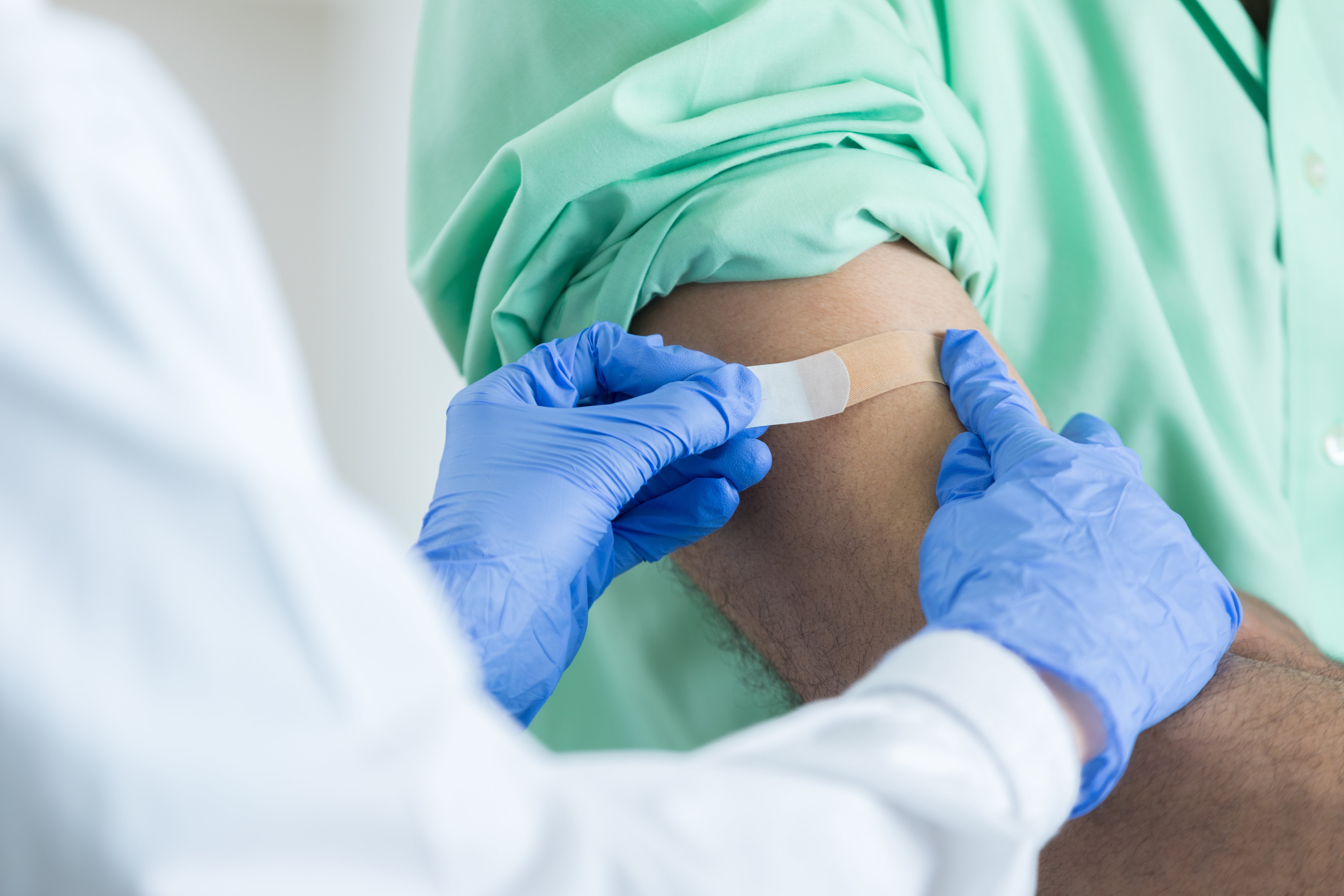 Closeup of unrecognizable pharmacist placing bandaid on customer's arm