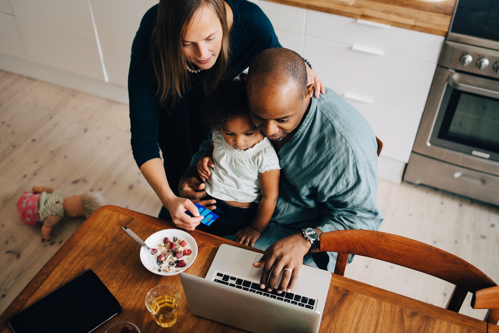 High angle view of parents with daughter shopping online on laptop at dining room