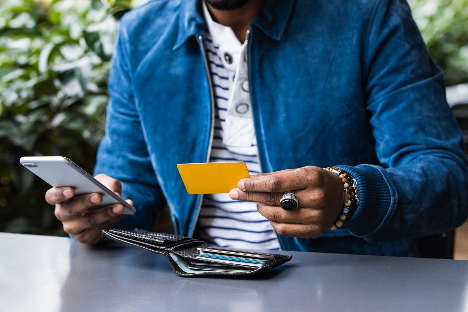 Close-up of man with credit card making mobile payment at sidewalk cafe