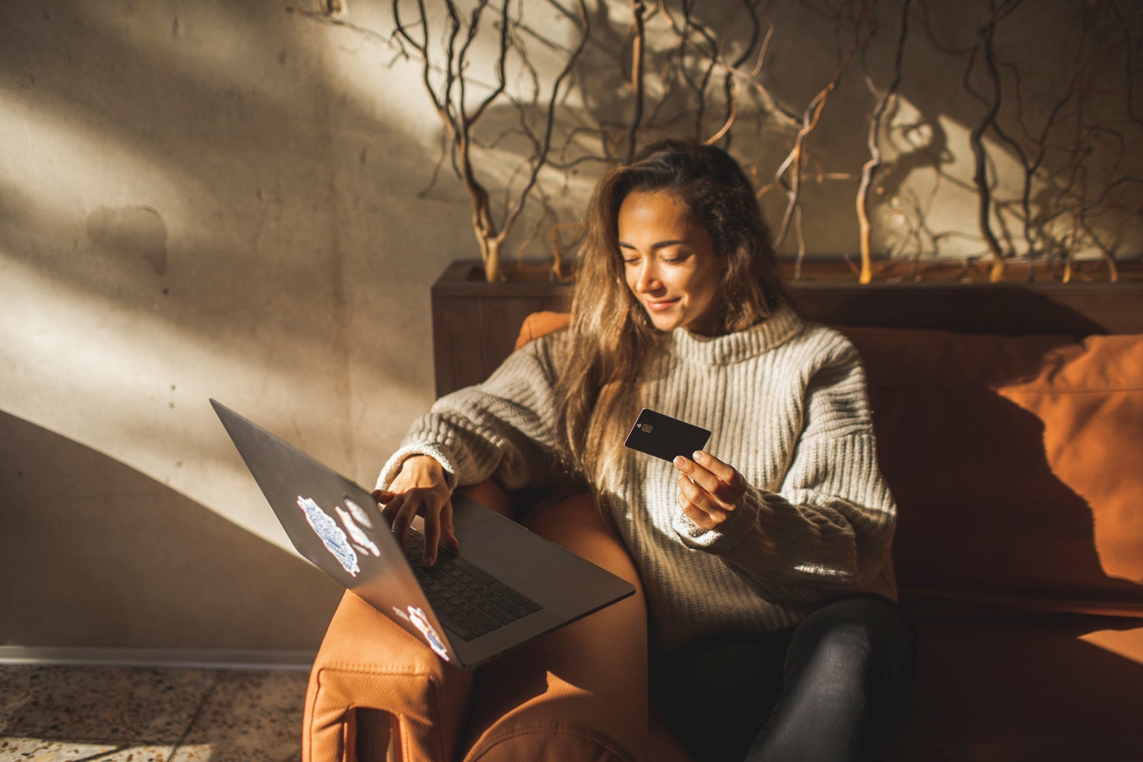 Young smiling Woman making online purchases in Cafe with Credit Card and Laptop