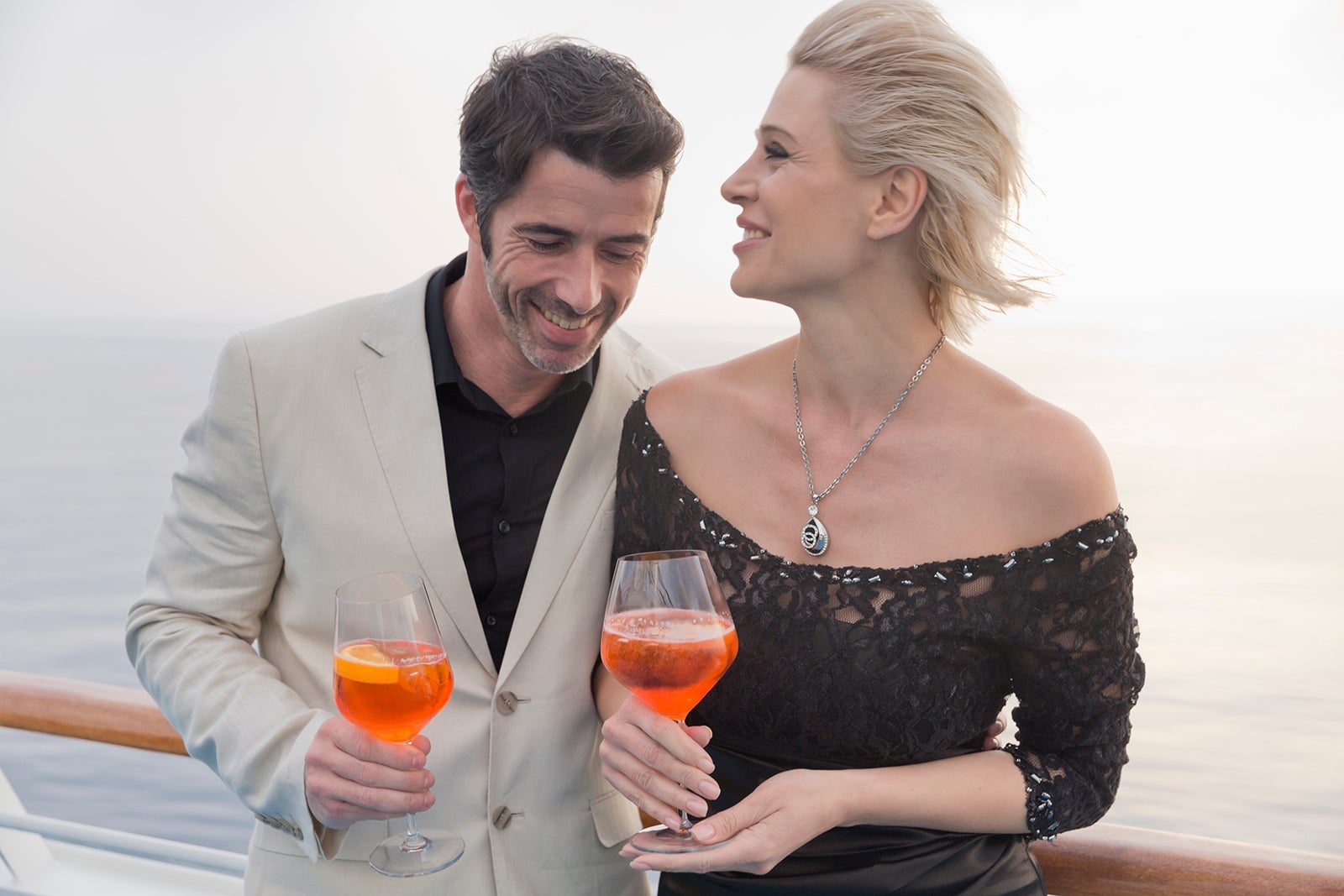Happy couple with aperitive standing on deck of a cruise liner
