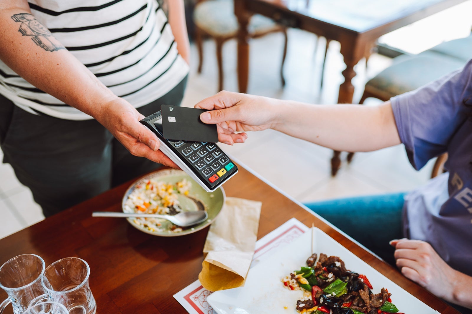 Contactless payment in restaurant. Wireless card reader scanning credit card from customer hand in cafe, high angle view