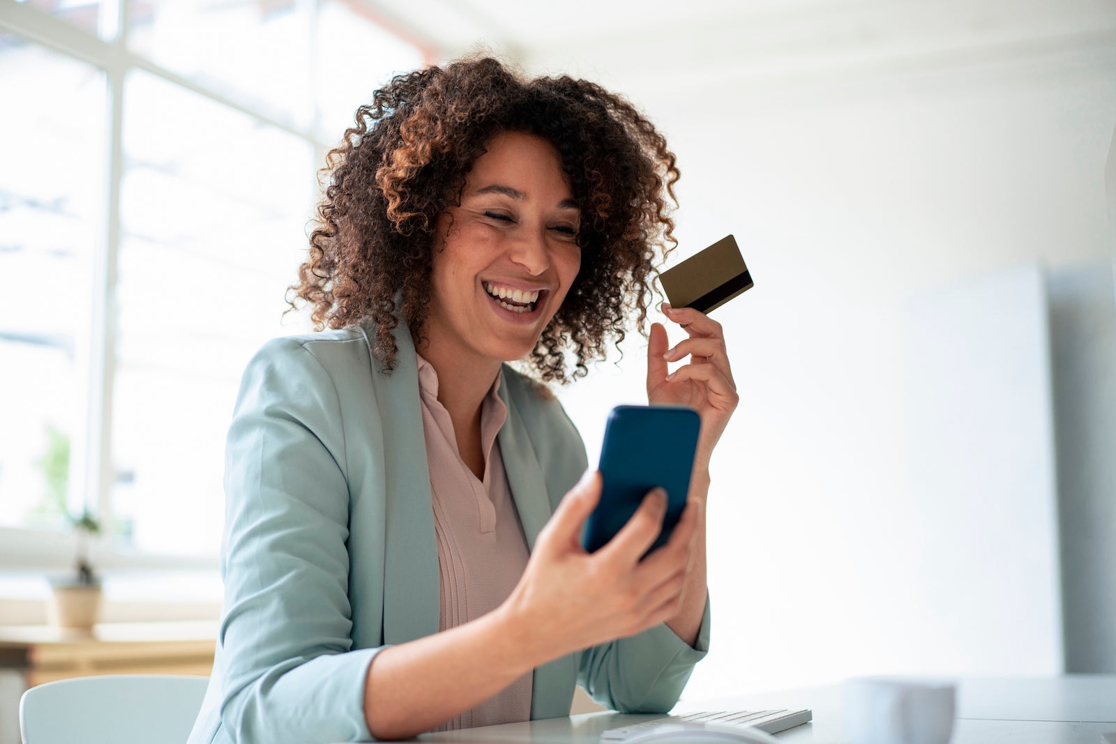 Happy businesswoman doing online payment through smart phone at workplace