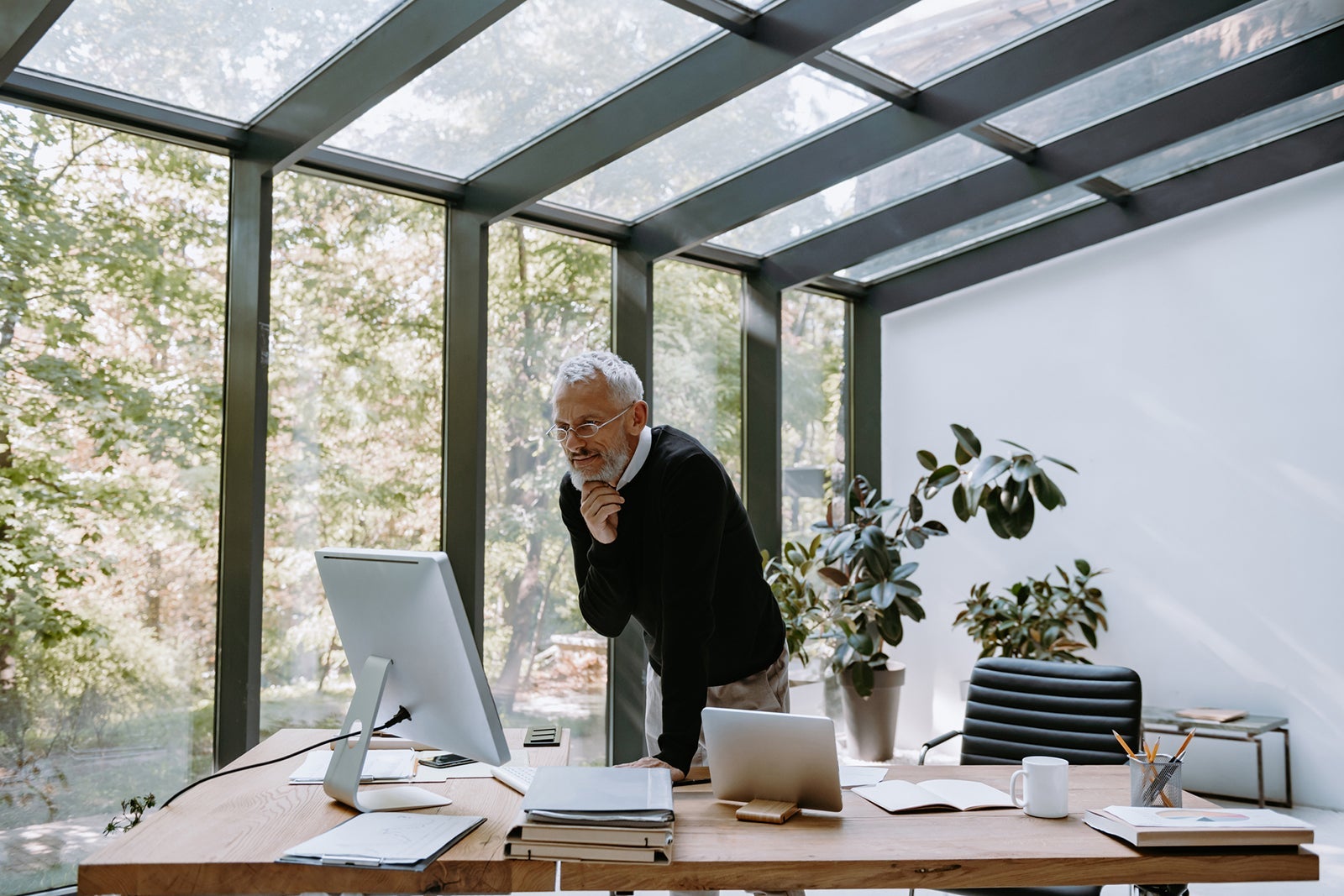Thoughtful mature man looking at computer monitor while working in the modern office