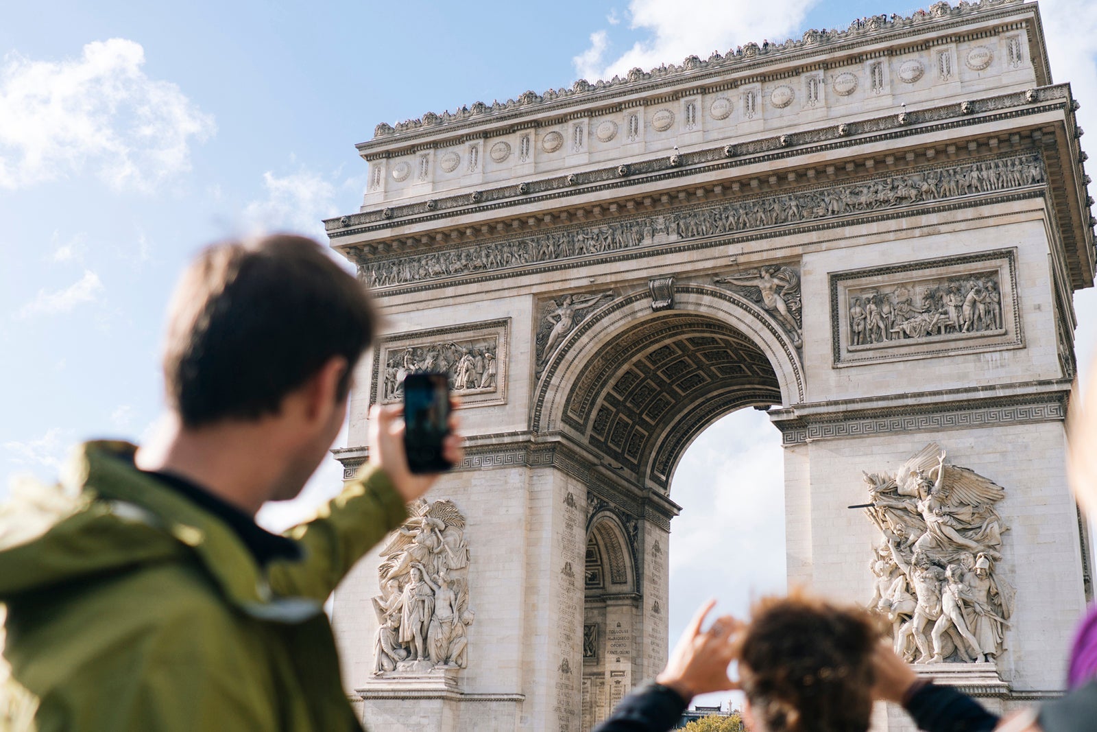 Man takes photo with smartphone of the Arc de Triomphe