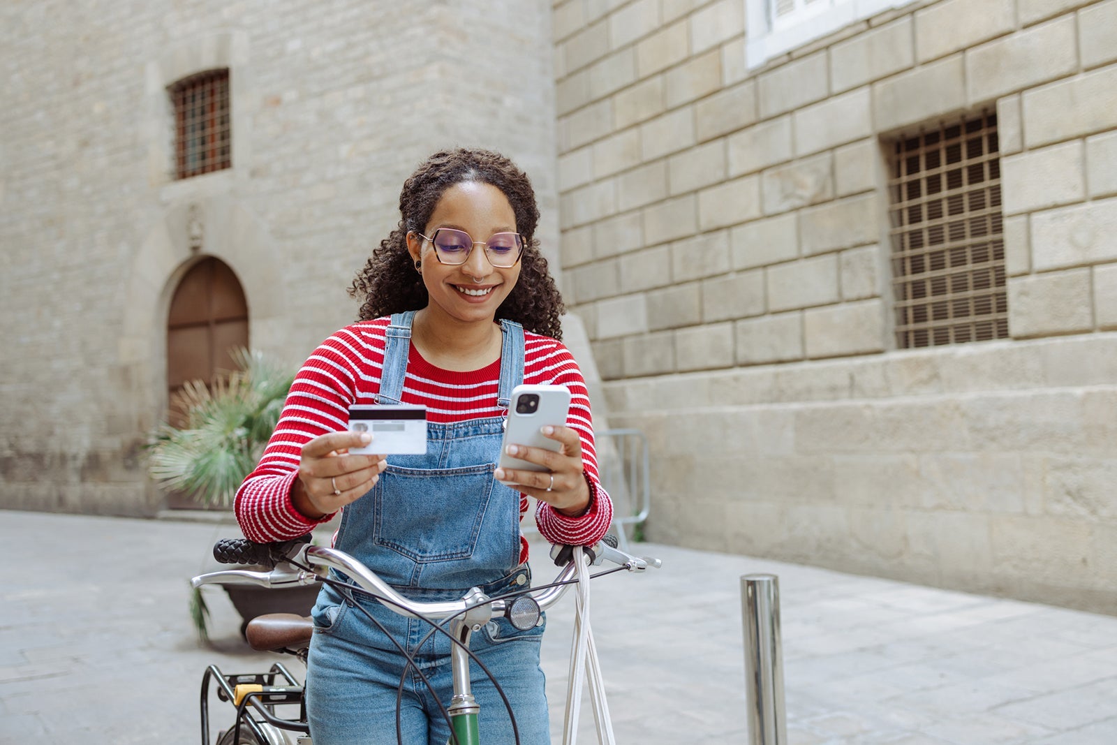 Young woman with a bicycle using online payment service