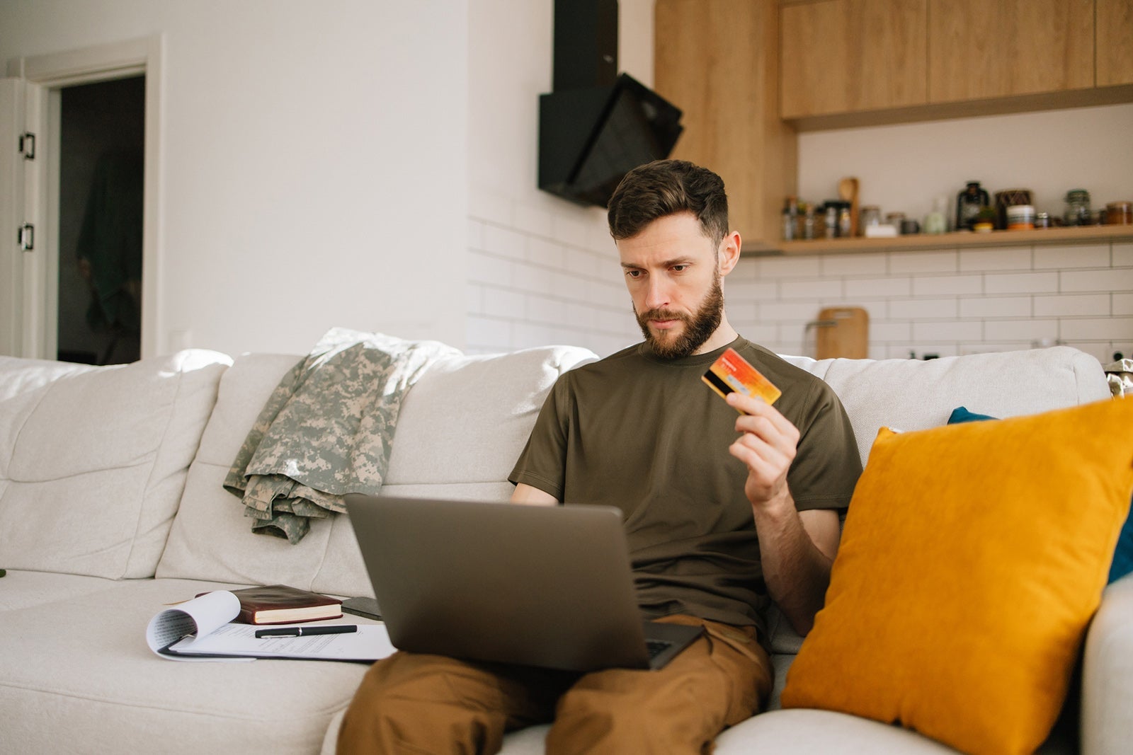 Young military man uses laptop to manage finances well at home