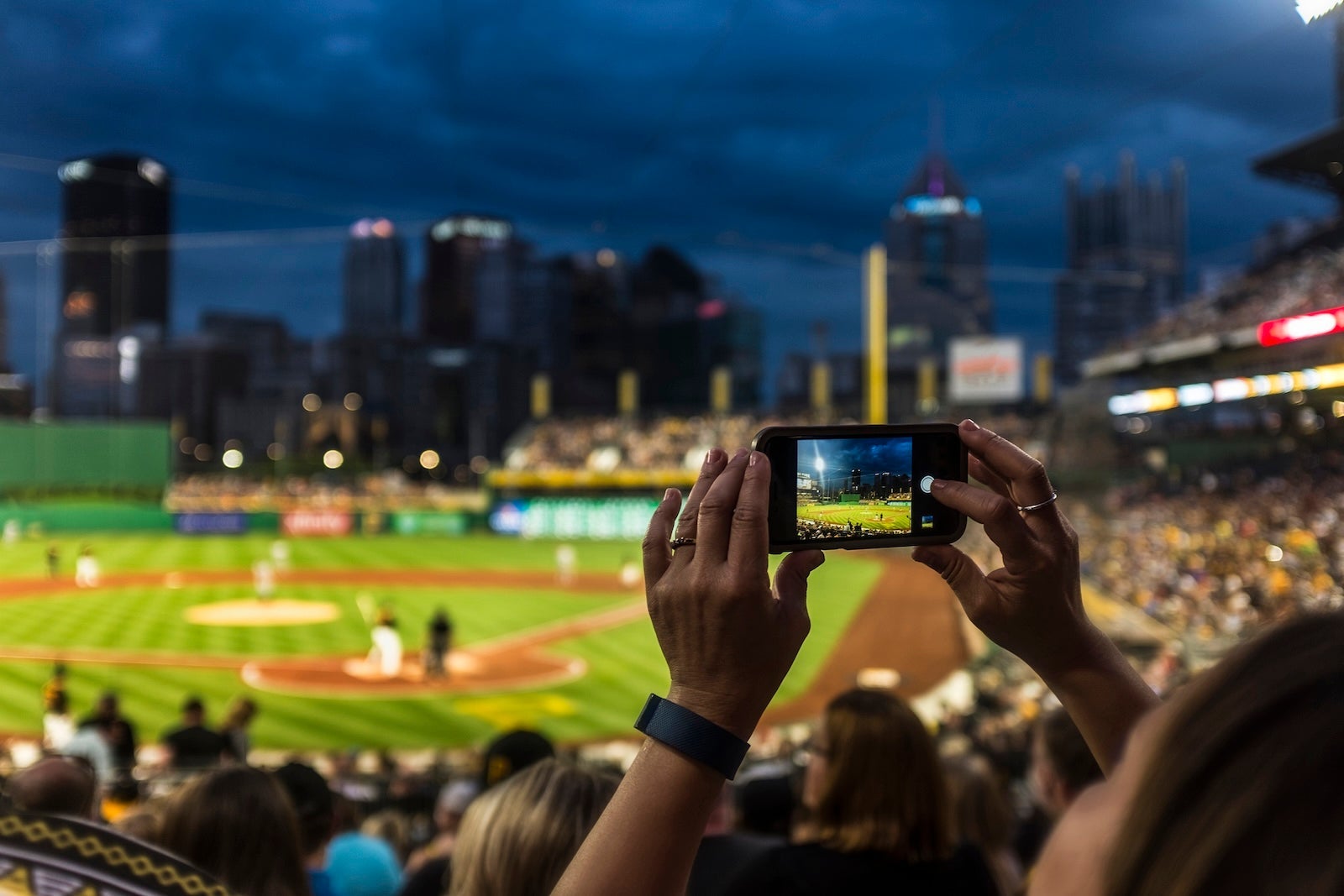 Hands of woman photographing baseball game with cell phone