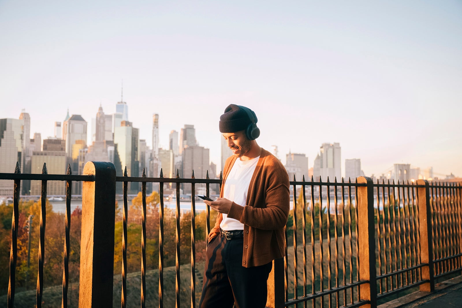 Man listening to music through wireless headphones with city skyline in background